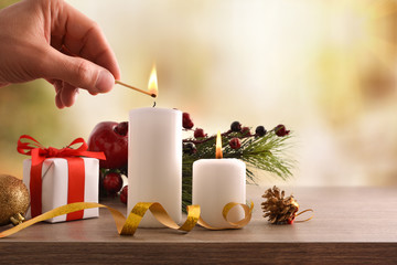 Hand lighting candles on decorated table at Christmas