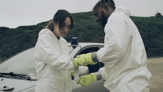 Man taping bacteriological protective suit gloves to a man outdoors