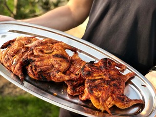 fried tobacco chickens on a tray in the hands of a guy