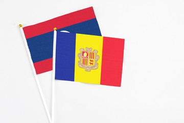 Andorra and Laos stick flags on white background. High quality fabric, miniature national flag. Peaceful global concept.White floor for copy space.