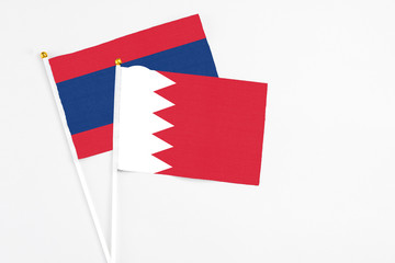 Bahrain and Laos stick flags on white background. High quality fabric, miniature national flag. Peaceful global concept.White floor for copy space.