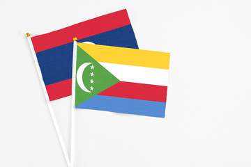 Comoros and Laos stick flags on white background. High quality fabric, miniature national flag. Peaceful global concept.White floor for copy space.