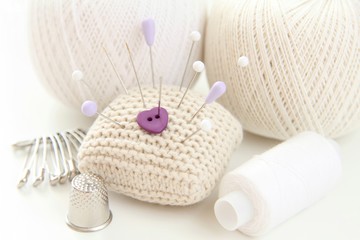 A heart-shaped button on a needle case with pins.