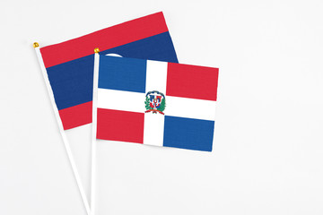Dominican Republic and Laos stick flags on white background. High quality fabric, miniature national flag. Peaceful global concept.White floor for copy space.