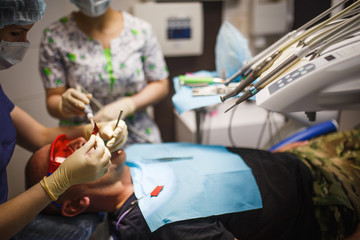 Dentist's hands in rubber gloves in the process of treatment and prosthetics. Doctor's hand with dental instrument.