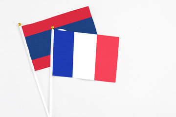 France and Laos stick flags on white background. High quality fabric, miniature national flag. Peaceful global concept.White floor for copy space.