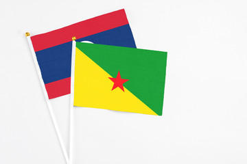 French Guiana and Laos stick flags on white background. High quality fabric, miniature national flag. Peaceful global concept.White floor for copy space.