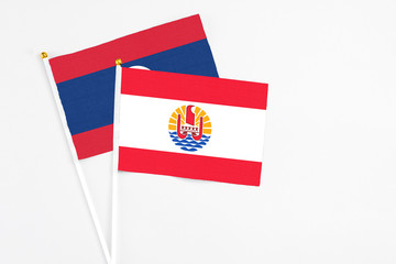 French Polynesia and Laos stick flags on white background. High quality fabric, miniature national flag. Peaceful global concept.White floor for copy space.