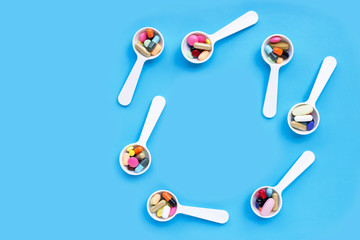 Colorful medicine pills, tablets and capsules on blue background.