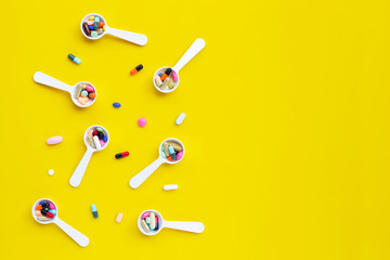 Colorful tablets with capsules and pills on yellow background.