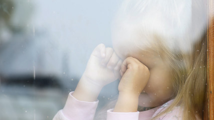 A child cries in the window of an old house