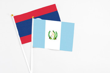 Guatemala and Laos stick flags on white background. High quality fabric, miniature national flag. Peaceful global concept.White floor for copy space.