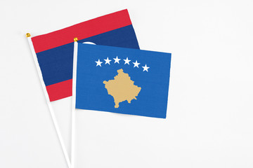 Kosovo and Laos stick flags on white background. High quality fabric, miniature national flag. Peaceful global concept.White floor for copy space.