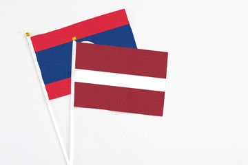 Latvia and Laos stick flags on white background. High quality fabric, miniature national flag. Peaceful global concept.White floor for copy space.