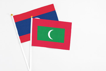 Maldives and Laos stick flags on white background. High quality fabric, miniature national flag. Peaceful global concept.White floor for copy space.