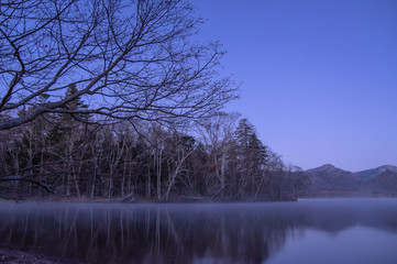 Naklejka na ściany i meble 薄明の湖岸。静水に映る風景。屈斜路湖、北海道、日本。