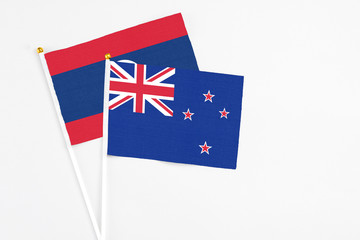 Fototapeta premium New Zealand and Laos stick flags on white background. High quality fabric, miniature national flag. Peaceful global concept.White floor for copy space.