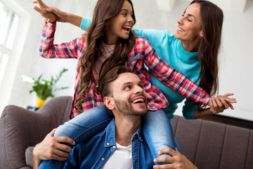 Playful spirit. Young gorgeous woman is playing with her cute little daughter and husband in their...