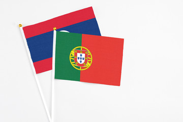 Portugal and Laos stick flags on white background. High quality fabric, miniature national flag. Peaceful global concept.White floor for copy space.