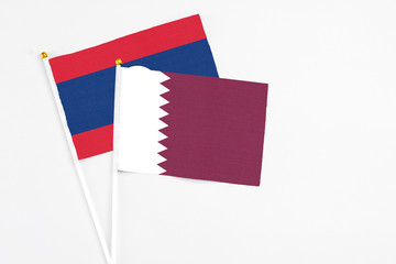 Qatar and Laos stick flags on white background. High quality fabric, miniature national flag. Peaceful global concept.White floor for copy space.