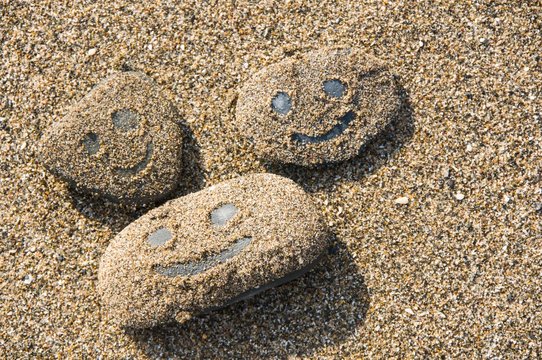 Smiling face pictured on sandy pebbles 