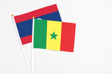 Senegal and Laos stick flags on white background. High quality fabric, miniature national flag. Peaceful global concept.White floor for copy space.