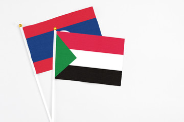 Sudan and Laos stick flags on white background. High quality fabric, miniature national flag. Peaceful global concept.White floor for copy space.