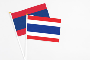 Thailand and Laos stick flags on white background. High quality fabric, miniature national flag. Peaceful global concept.White floor for copy space.