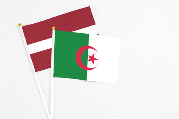 Algeria and Latvia stick flags on white background. High quality fabric, miniature national flag....