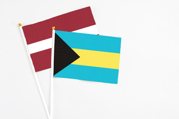 Bahamas and Latvia stick flags on white background. High quality fabric, miniature national flag. Peaceful global concept.White floor for copy space.