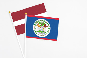 Belize and Latvia stick flags on white background. High quality fabric, miniature national flag. Peaceful global concept.White floor for copy space.