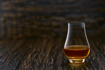 Full glass of whiskey on a wooden table, selective focus with copy space.