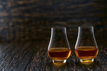 Two glasses of whiskey  served on wooden table with copy space.