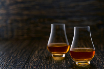 Two glasses of whiskey  served on wooden table, selective focus.