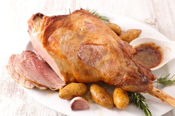 roasted lamb leg with potato and sauce on wood background