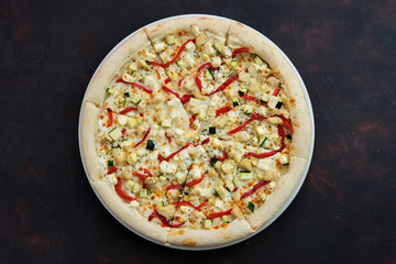 Close up view of pizza with chicken, bell pepper, squash and feta