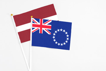 Fototapeta premium Cook Islands and Latvia stick flags on white background. High quality fabric, miniature national flag. Peaceful global concept.White floor for copy space.
