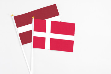 Fototapeta na wymiar Denmark and Latvia stick flags on white background. High quality fabric, miniature national flag. Peaceful global concept.White floor for copy space.