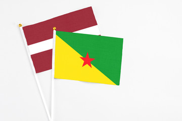 French Guiana and Latvia stick flags on white background. High quality fabric, miniature national flag. Peaceful global concept.White floor for copy space.