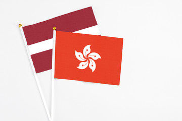 Hong Kong and Latvia stick flags on white background. High quality fabric, miniature national flag. Peaceful global concept.White floor for copy space.