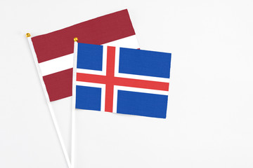 Obraz premium Iceland and Latvia stick flags on white background. High quality fabric, miniature national flag. Peaceful global concept.White floor for copy space.