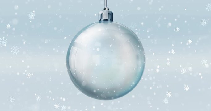 Isolated empty glass ball decoration on bright blue background at snowfall, 4k seamless loop animation