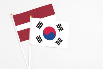 South Korea and Latvia stick flags on white background. High quality fabric, miniature national flag. Peaceful global concept.White floor for copy space.