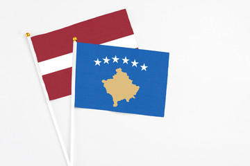 Kosovo and Latvia stick flags on white background. High quality fabric, miniature national flag. Peaceful global concept.White floor for copy space.