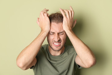 Portrait of man suffering from head ache on color background