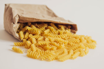 Spiral pasta in a paper bag on a white background. Top view. Copy, empty space for text