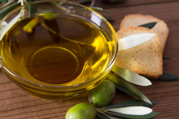 bowl of extra virgin olive oil with olives and leaves