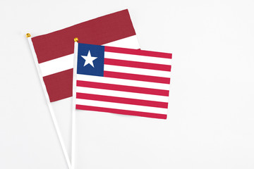 Liberia and Latvia stick flags on white background. High quality fabric, miniature national flag. Peaceful global concept.White floor for copy space.