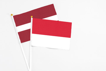 Monaco and Latvia stick flags on white background. High quality fabric, miniature national flag. Peaceful global concept.White floor for copy space.