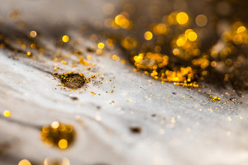 Macro Close Up Shot Of Golden Wet Glitter. Golden Space Glittering Particle Background. Golden sand or dust abstract formations. Colorful sparkling paints. Oil ink of yellow and gold. Pure Liquid Gold